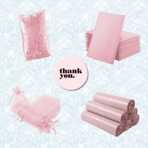 A flat lay of pink packaging materials including shredded paper, bubble mailers, organza bags, poly mailers, and a circular card in the center that says thank you. Background features a light blue floral pattern.